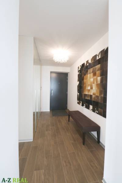 Flur in einer 3-Zimmer-Wohnung mit Holzboden und eleganter Beleuchtung.