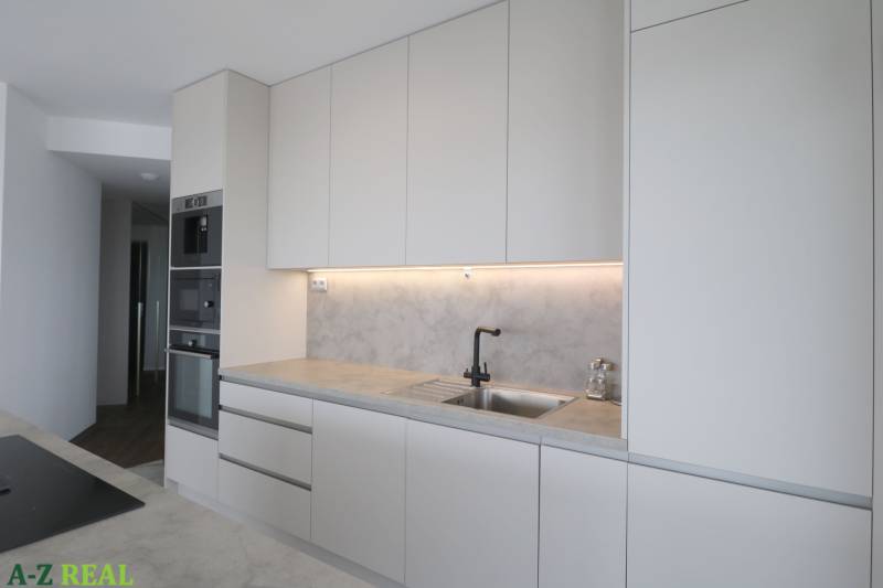 Küche in einer 3-Zimmer-Wohnung mit weißen Schränken und eingebauten Geräten.