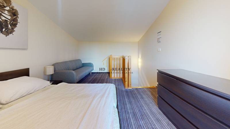 Schlafzimmer in einer Zweizimmerwohnung mit Bett, Sofa und Kommode.