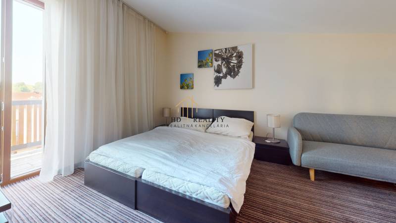 Helles Schlafzimmer in einer 2-Zimmer-Wohnung mit Bett, Sofa und Balkon.