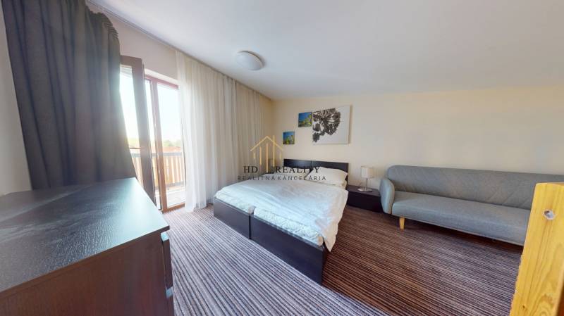 Schlafzimmer in einer 2-Zimmer-Wohnung mit Bett, Sofa und Balkon.