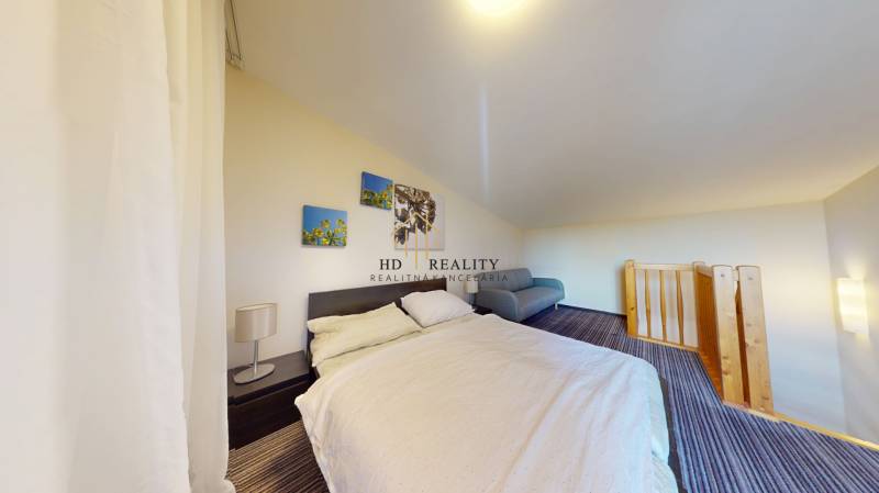 Schlafzimmer in einer 2-Zimmer-Wohnung mit einem bequemen Bett und einem Geländer an der Treppe.