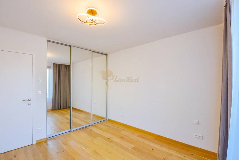 Ein Zimmer mit Holzboden, einem Spiegelschrank und einem Vorhang in einer 3-Zimmer-Wohnung.