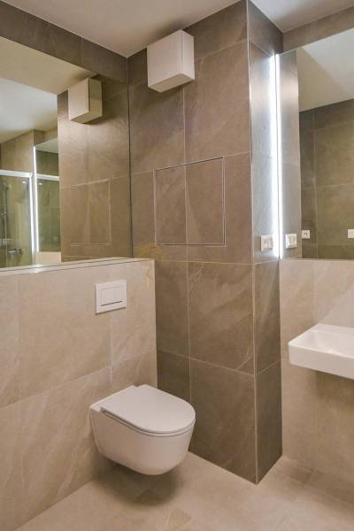 Badezimmer mit hängender Toilette und Duschkabine in einer 3-Zimmer-Wohnung.