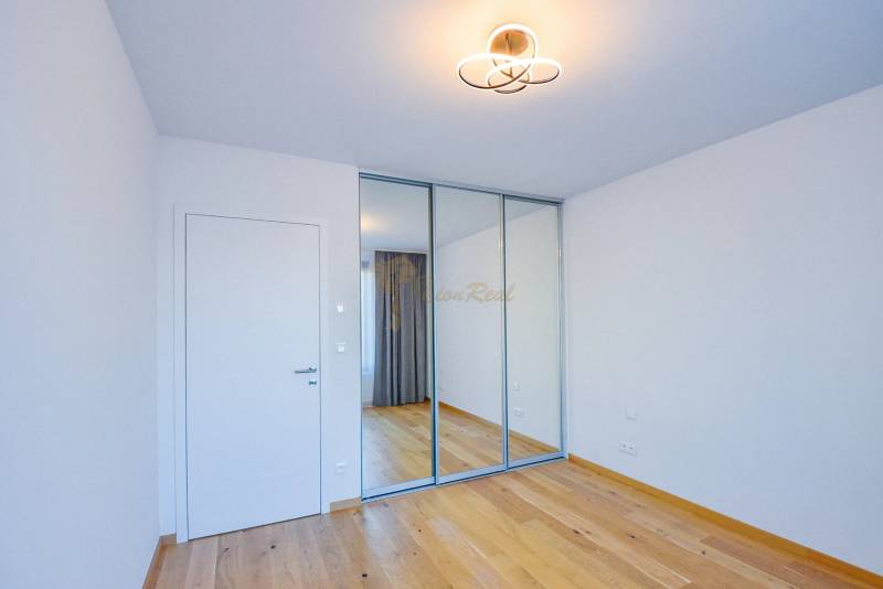 Ein Zimmer mit Holzboden, einem Spiegelschrank und einfacher Beleuchtung in einer 3-Zimmer-Wohnung.