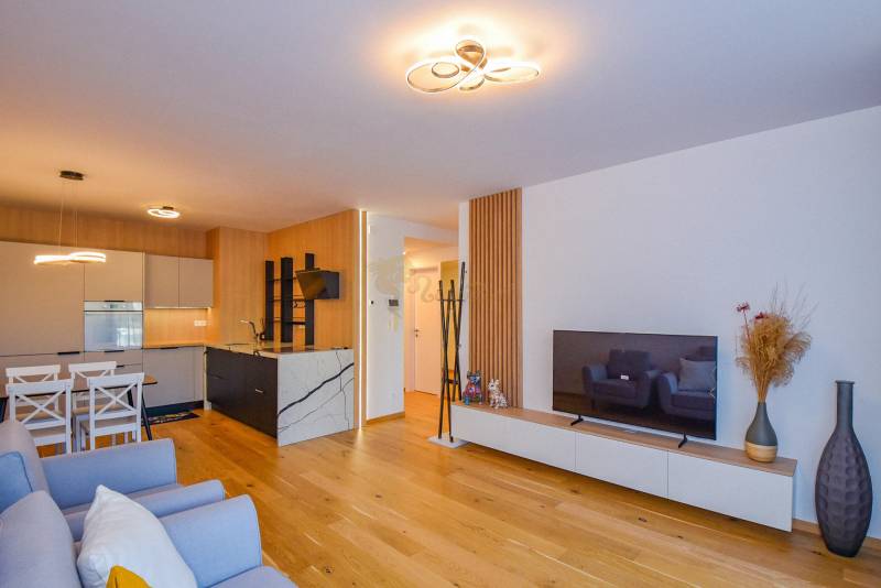 Wohnzimmer mit offener Küche; Holzboden, Esstisch, Fernseher, 3-Zimmer-Wohnung.