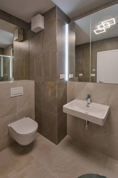 Badezimmer mit hängendem WC, Waschbecken und Dusche in einer 3-Zimmer-Wohnung.