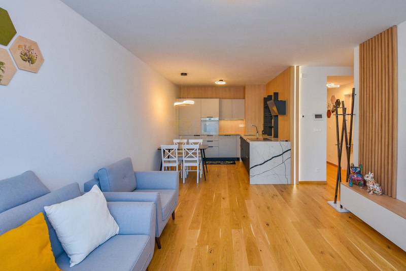 Wohnzimmer in einer 3-Zimmer-Wohnung mit Küche, helle Holzböden und bequeme Sitzgelegenheiten.