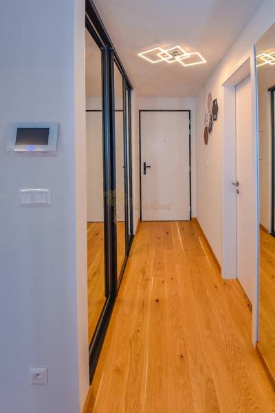 Flur mit Spiegelschränken in einer 3-Zimmer-Wohnung, weiße Wände, Holzboden.