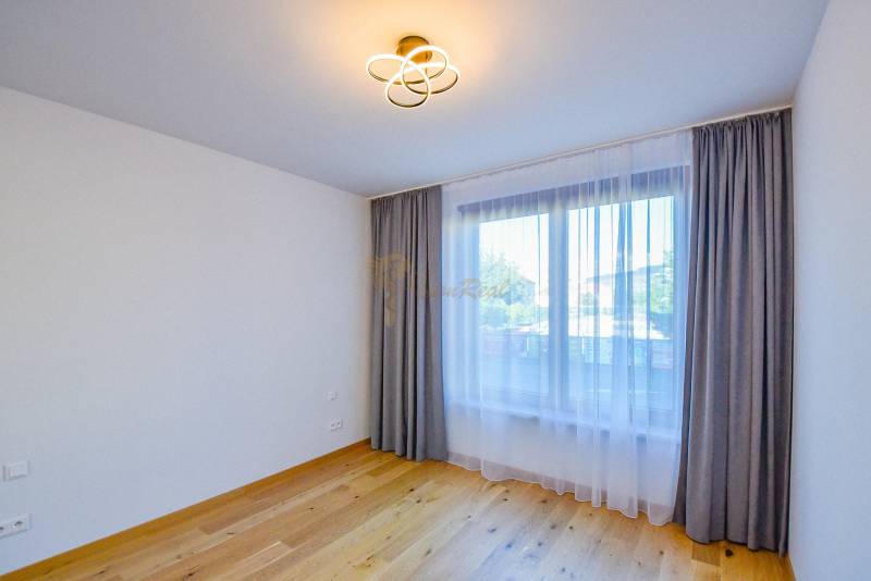 Unmöbliertes Zimmer mit Holzboden und Vorhängen in einer 3-Zimmer-Wohnung.