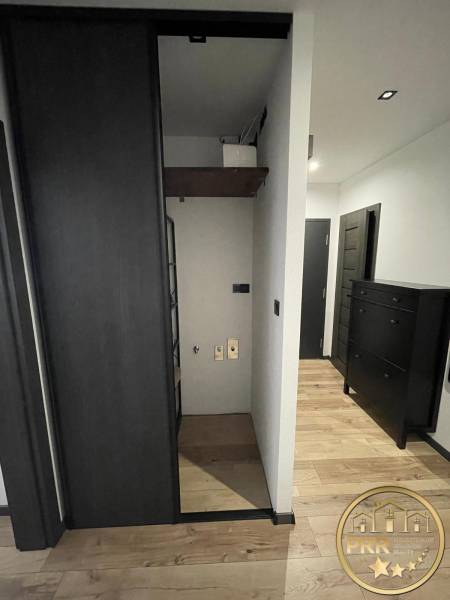 Der Flur in der 3-Zimmer-Wohnung mit Holzboden und dunklen Möbeln.