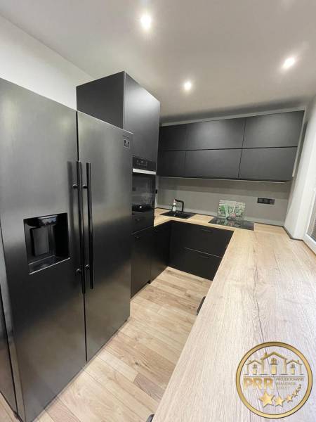 Küche in einer 3-Zimmer-Wohnung mit schwarzen Geräten und Holzboden.