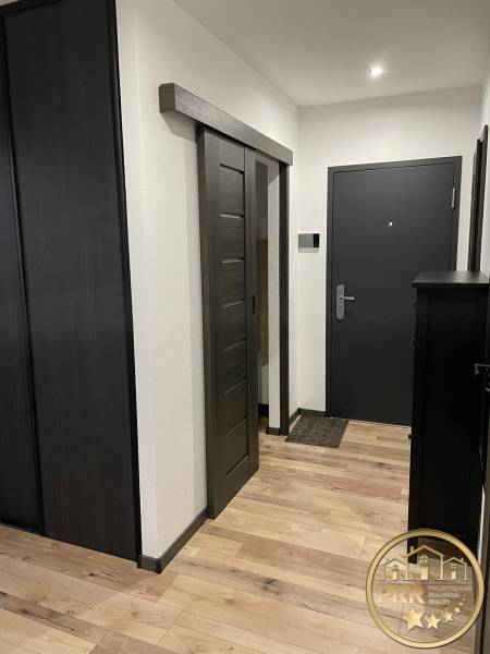 Eingangsflur zu einer 3-Zimmer-Wohnung mit Holzböden und dunklen Schiebetüren.