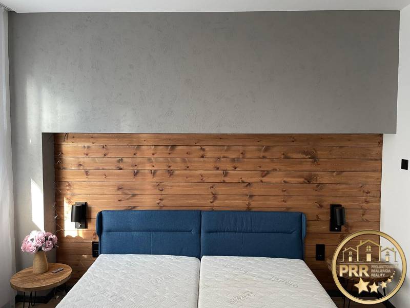 Helles Schlafzimmer in einer 3-Zimmer-Wohnung mit einer Holzwand und einem blauen Bett.