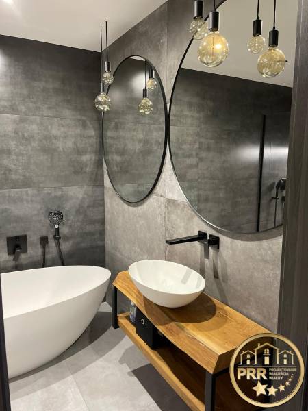 Badezimmer in einer 3-Zimmer-Wohnung mit stilvollen Spiegeln, Badewanne und Waschtisch aus Holz.