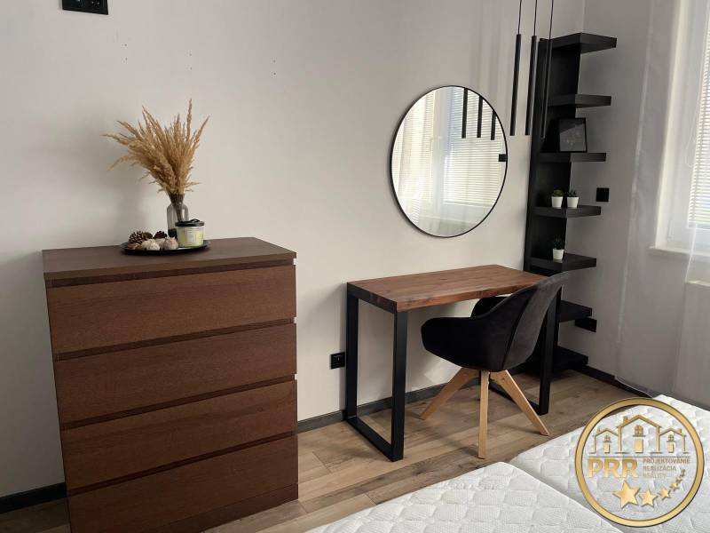 Schlafzimmer mit Kommode, Spiegel und Schreibtisch in einer 3-Zimmer-Wohnung.