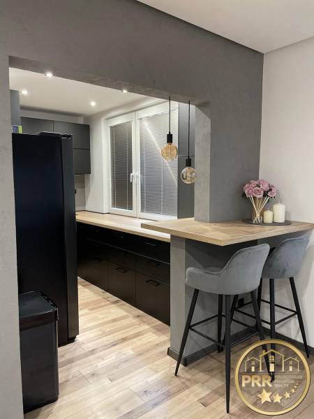 Stilvolle Küche mit Holzboden und Bartresen in einer 3-Zimmer-Wohnung.