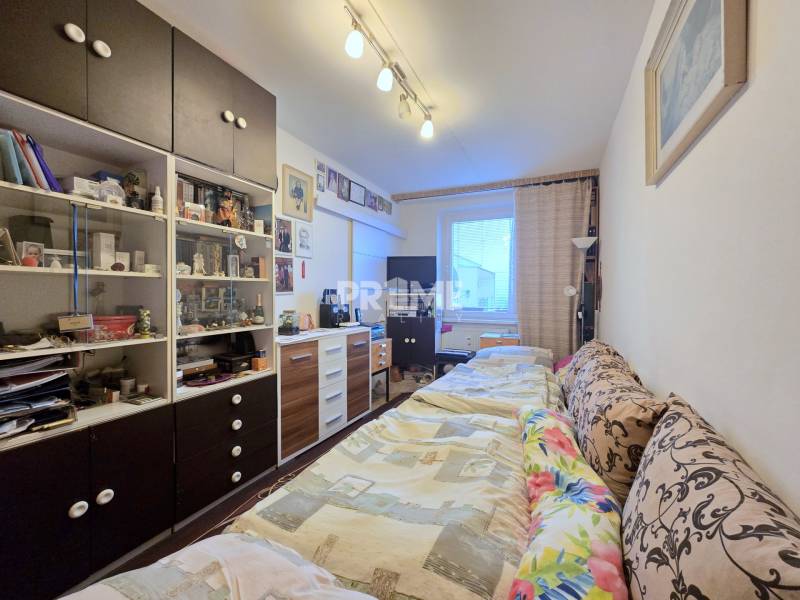 Ein Zimmer in einer 3-Zimmer-Wohnung mit einem Schrank, einem Bett und dekorativen Gegenständen.