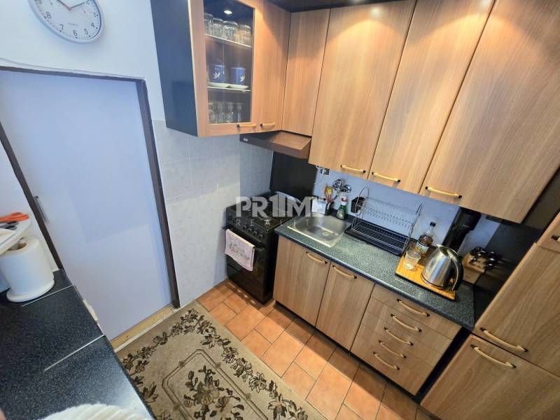 Küchenzeile in einer 3-Zimmer-Wohnung mit Holzschränken und schwarzen Arbeitsplatten.