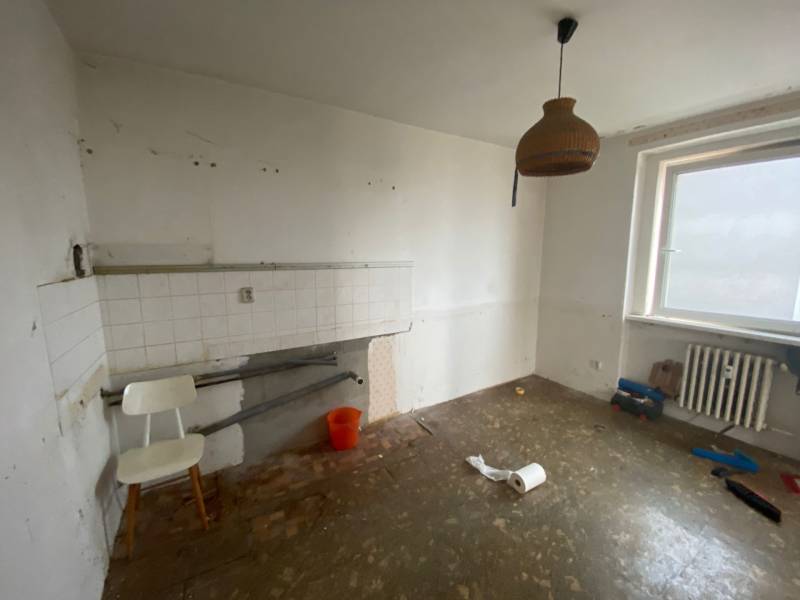 Eine leere Küche mit einfacher Ausstattung in einer 3-Zimmer-Wohnung, weiße Wände, Heizkörper.