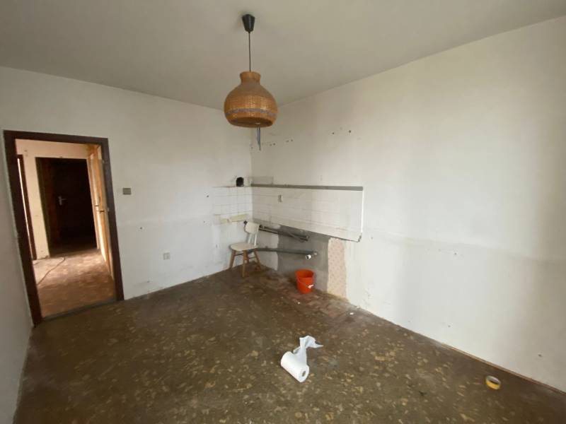 Eine leere Küche in einer 3-Zimmer-Wohnung mit einem ungewöhnlichen Kronleuchter und einem unfertigen Boden.