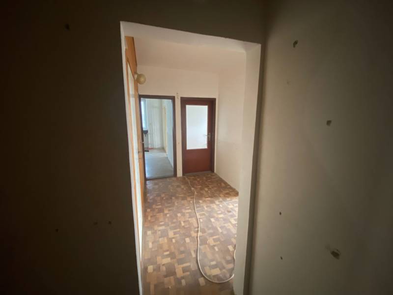 Flur in einer 3-Zimmer-Wohnung mit Holzboden und zwei Zimmern.