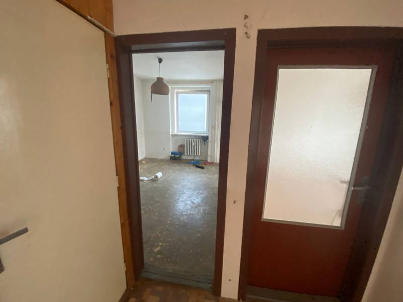 Ein Zimmer in einer 3-Zimmer-Wohnung mit nacktem Boden und einem Fenster.