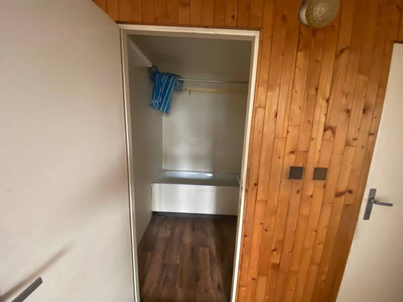 Badezimmer in einer 3-Zimmer-Wohnung mit Holzverkleidung und Badewanne.