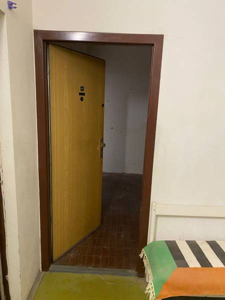 Offene Tür in einer 3-Zimmer-Wohnung mit Fliesenboden und einer Bank mit buntem Überwurf.