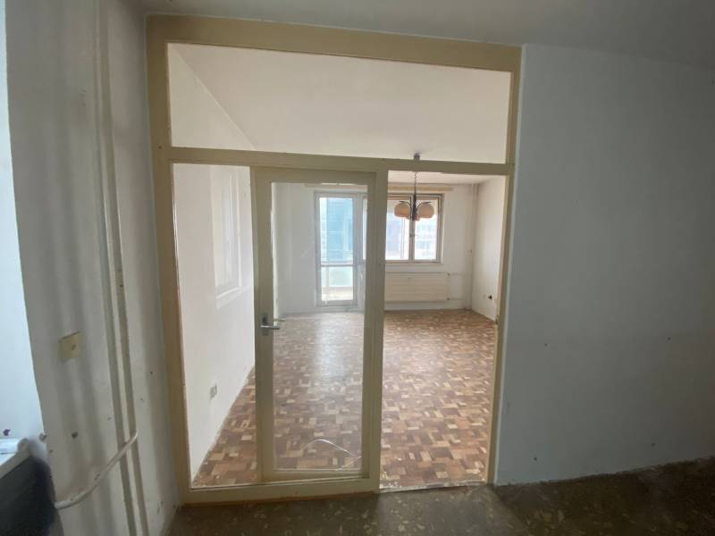 Das Interieur einer 3-Zimmer-Wohnung mit Parkettboden und einem großen Fenster.
