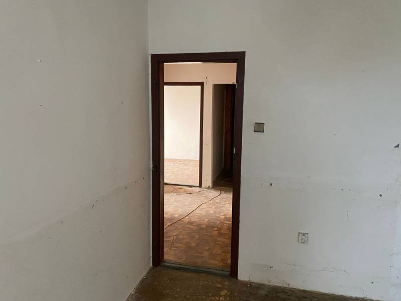 Eine leere Inneneinrichtung mit offenen Türen und Parkettboden in einer 3-Zimmer-Wohnung.
