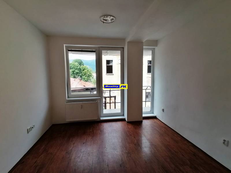 Ein leerer Raum mit Holzboden und großen Fenstern in einer 2-Zimmer-Wohnung.