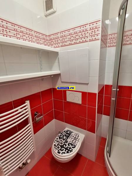 Badezimmer in einer 2-Zimmer-Wohnung mit auffälligen roten und weißen Fliesen.