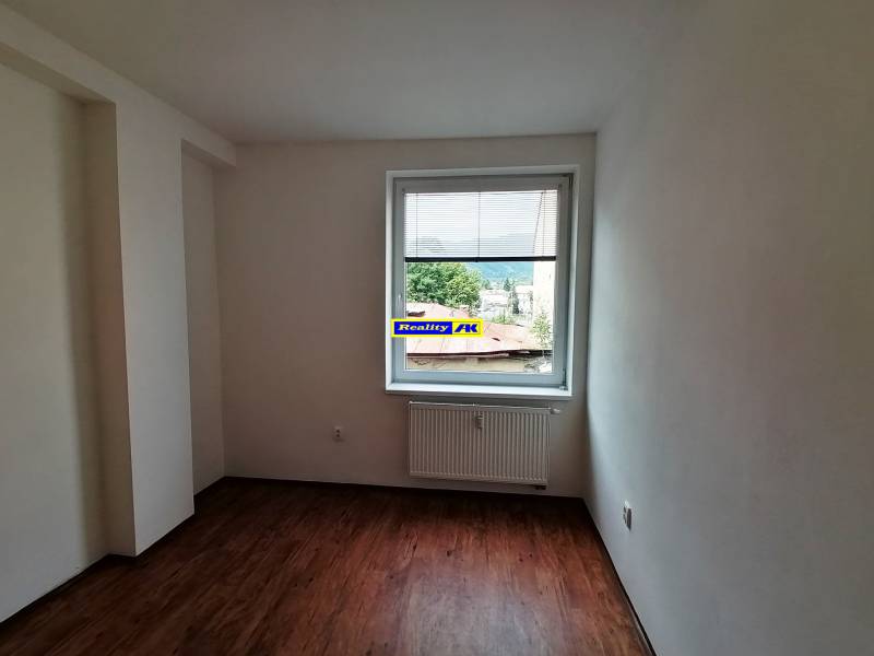 Ein leerer Raum mit Holzboden und einem Fenster in einer Zweizimmerwohnung.