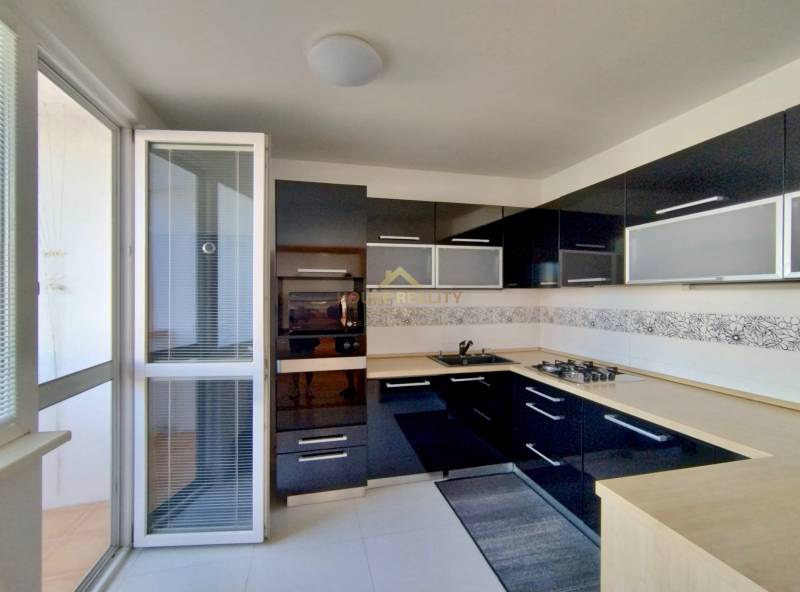 Küche mit dunklen Schränken und eingebauten Geräten in einer 3-Zimmer-Wohnung.