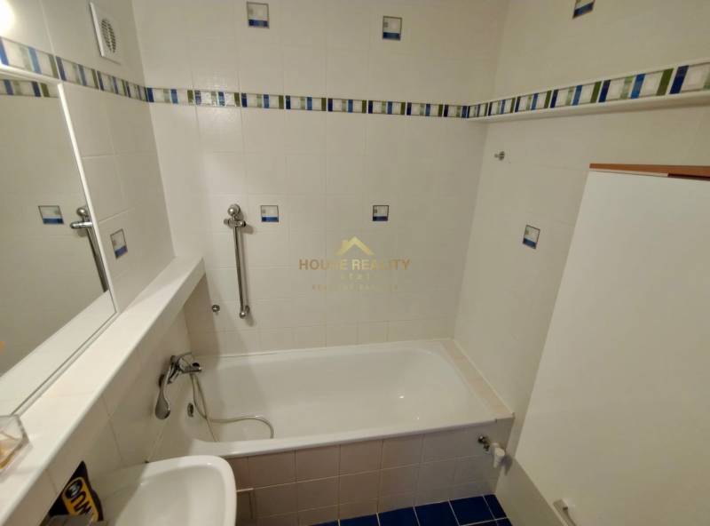 Ein Badezimmer mit hellen Fliesen, einer Badewanne und einem Waschbecken in einer 3-Zimmer-Wohnung.