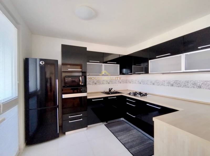Küche in einer 3-Zimmer-Wohnung mit schwarzen glänzenden Schränken und einem Eckherd.