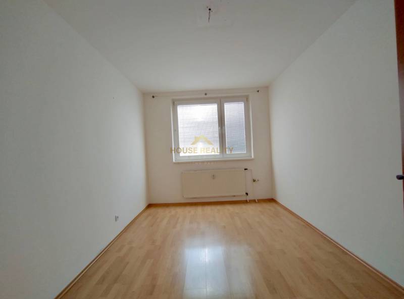 Ein Zimmer in einer 3-Zimmer-Wohnung mit einem Boden in Holzoptik und weißen Wänden.