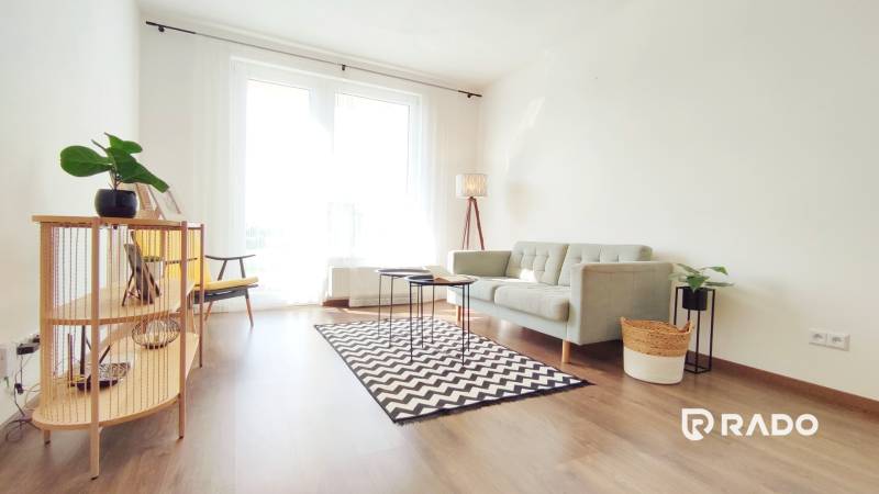 Heller Wohnbereich mit Sofa und Sessel in einer Zweizimmerwohnung.