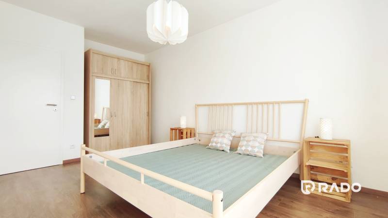 Schlafzimmer mit Holzbett, Einbauschrank und Nachttischen in einer 2-Zimmer-Wohnung.