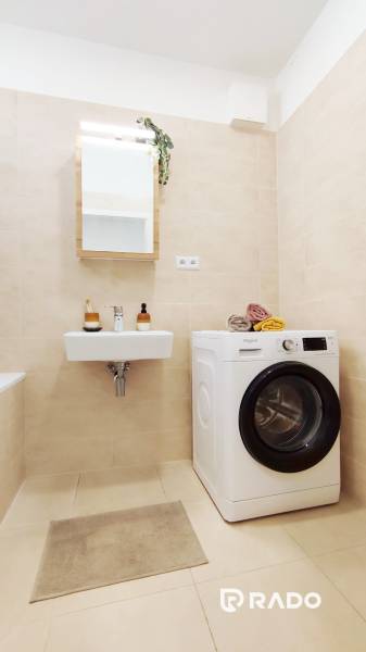 Badezimmer in einer 2-Zimmer-Wohnung mit Waschbecken, Waschmaschine und Handtuchhalter.