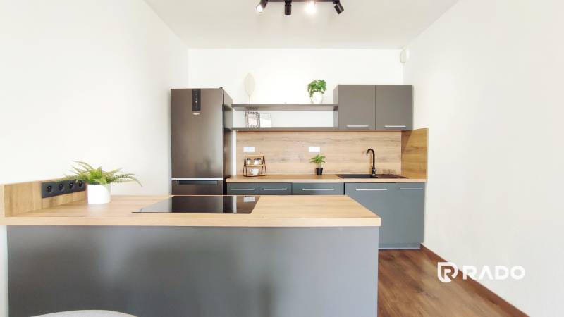 Küche in einer 2-Zimmer-Wohnung mit dunkelgrauer und hölzerner Küchenzeile.