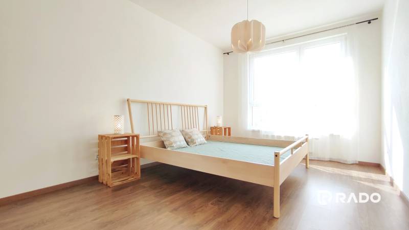 Helles Schlafzimmer mit Holzbett und Nachttischen in einer Zweizimmerwohnung.