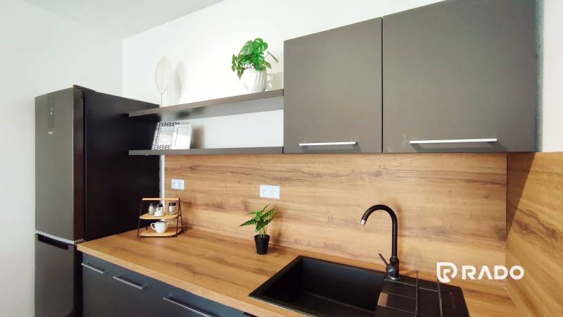 Küche in einer 2-Zimmer-Wohnung mit grauen Schränken und einer Holzarbeitsplatte.