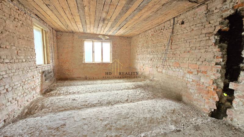 Unverputzte Ziegelwände in einem Einfamilienhaus, laufende Renovierung, natürliches Licht aus den Fenstern.