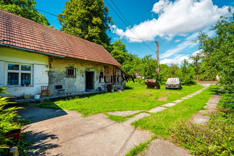 Ein Einfamilienhaus in Lúky mit einem grasbewachsenen Hof und Bäumen im Hintergrund.