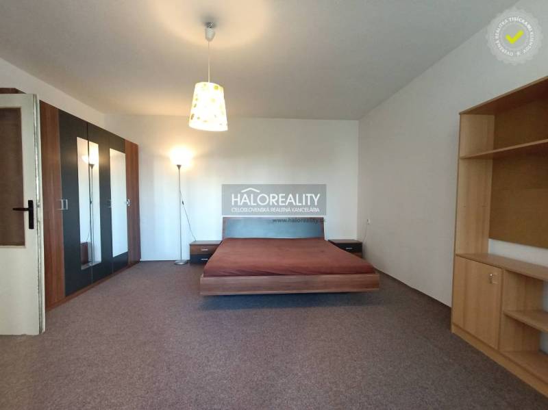 Stilvolles Interieur einer Einzimmerwohnung mit Bett, Einbauschrank und Regalen.