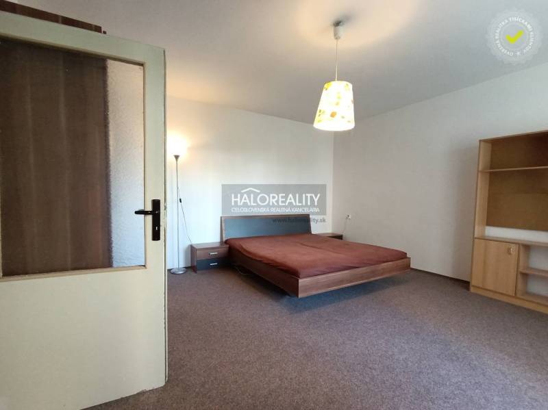Helles Schlafzimmer in einer Einzimmerwohnung mit Bett, Lampe und Möbeln.