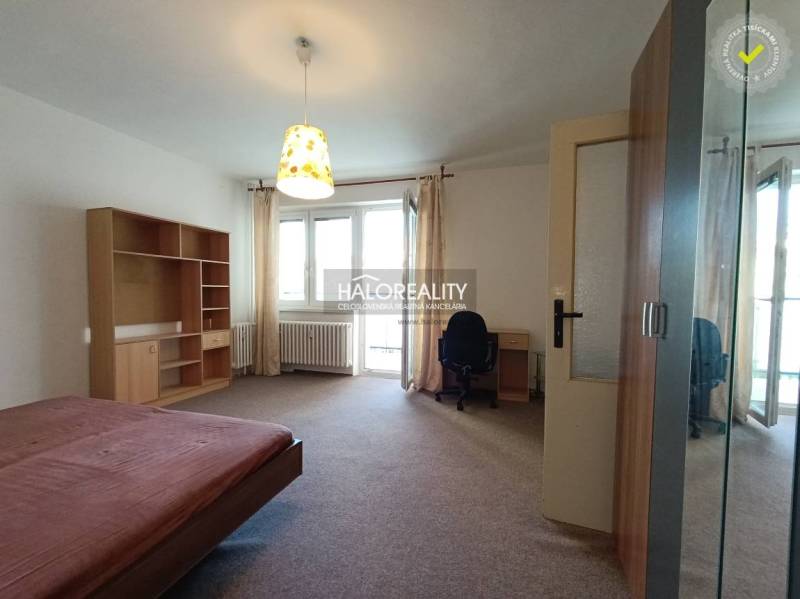 Schlafzimmer in einer Einzimmerwohnung mit Einbauschrank und Schreibtisch.