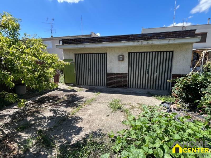 Die Garage bei einem Einfamilienhaus in Kolárovo, umgeben von Grün und Bäumen.